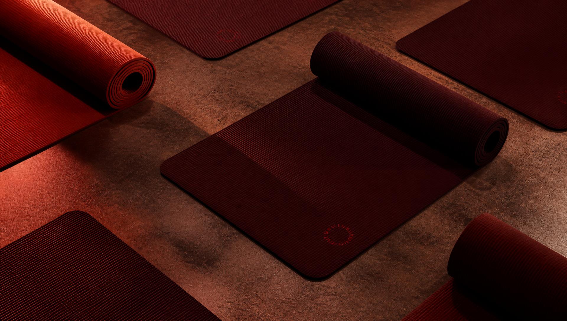 Mats de pilates alineados en repetición sobre piso oscuro bajo luz roja cálida